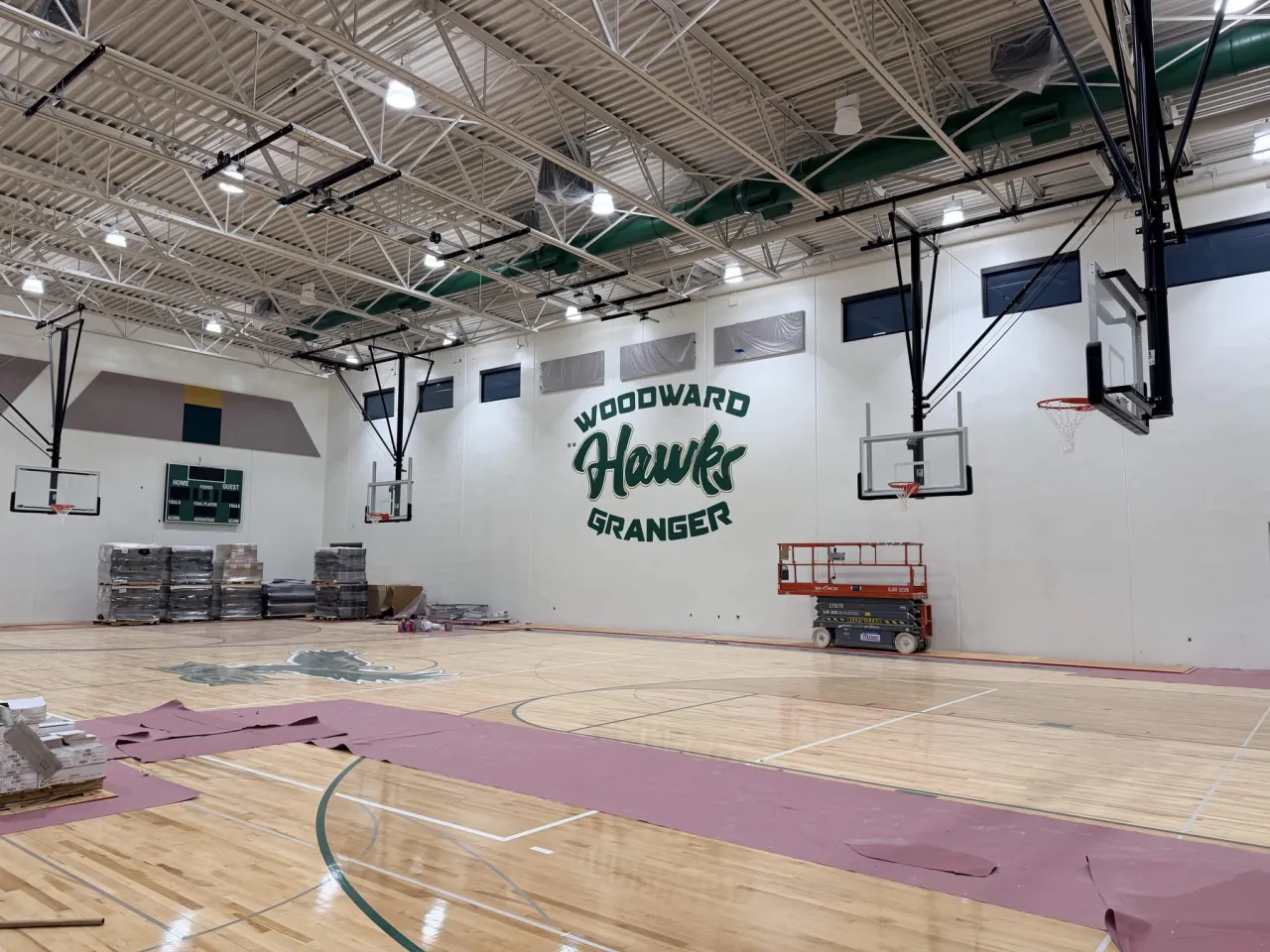 Wide angled view of the Woodward Granger gym showing the Hawks mural on the far wall between the two basketball hoops