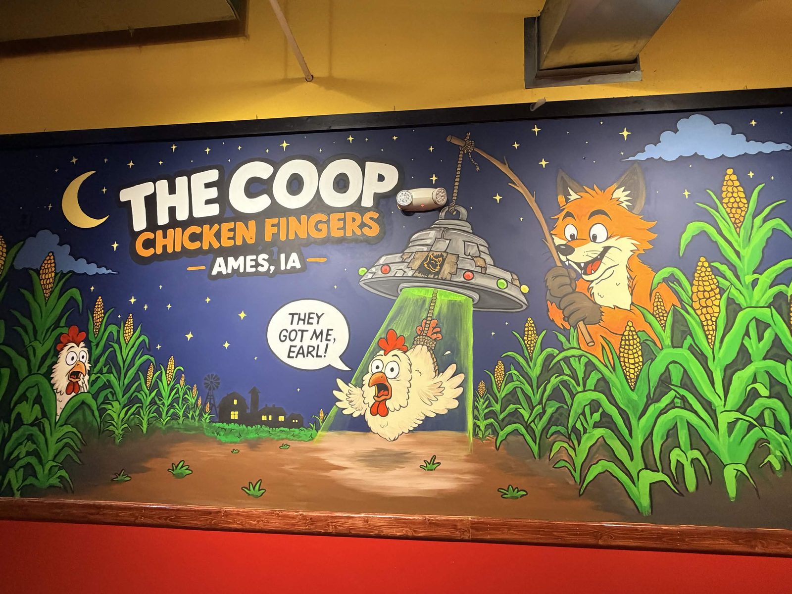 Detail of the Coop Chicken Fingers mural: a fox using a fishing rod while a chicken is lifted toward the flying saucer