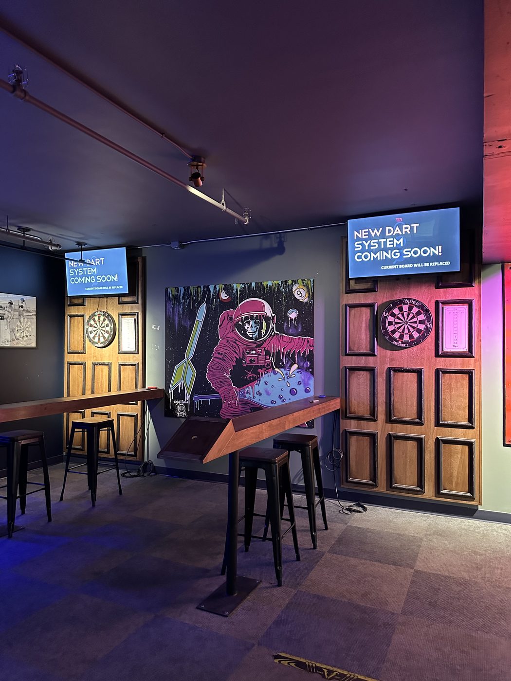 The astronaut artwork mounted between two dartboard stations at Ricochet