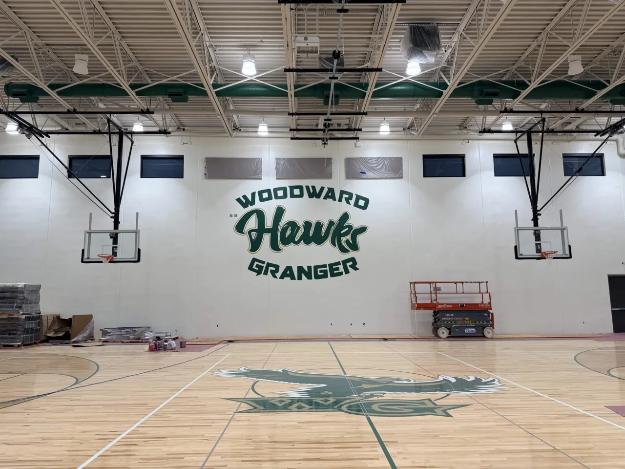 The finished Woodward Granger Hawks wall seen straight on across the basketball court, with the hawk and WG floor graphic in front of it
