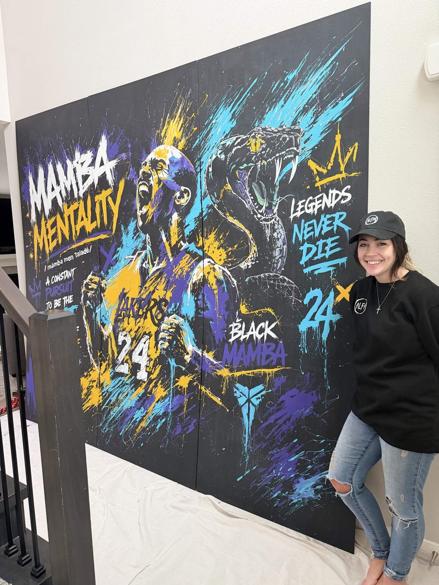 The Mamba Mentality panels seen from an angle during installation, with Amanda Fatino standing at the wall