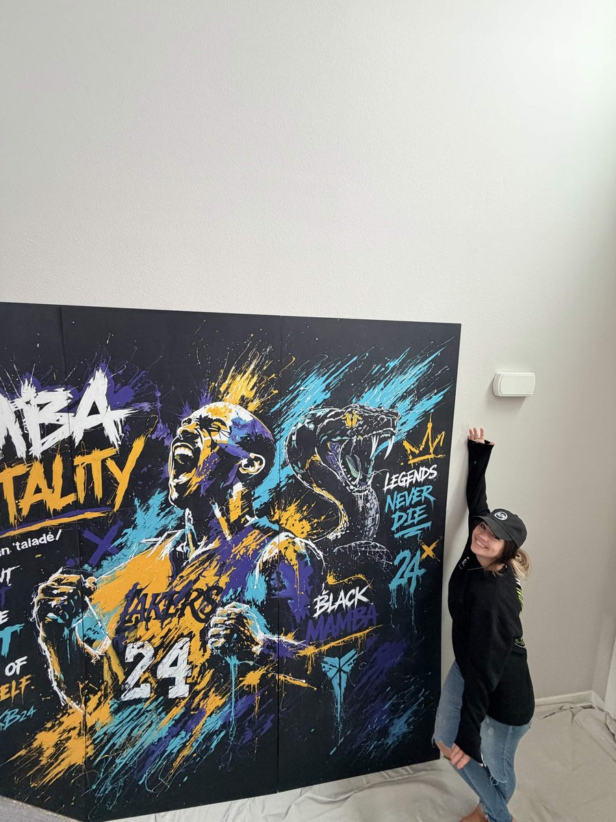 Amanda Fatino standing beside the finished Mamba Mentality panels with drop cloths on the floor