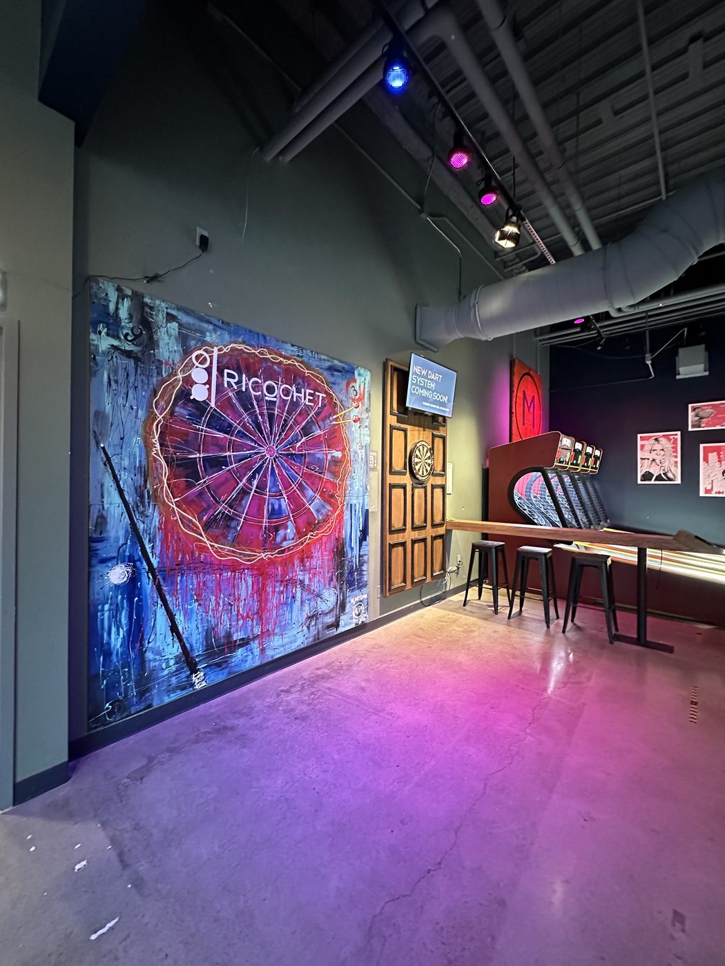 The Ricochet dartboard artwork mounted on the venue wall beside the dart lanes